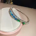 Gros plan d'un bracelet élastique argenté à deux couches avec des pierres bleues et vertes - Style 60 Jonc (Strass Dégradé)