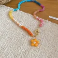 Close-up of a colorful crystal beaded necklace with a yellow resin flower charm. - Orange (#34)