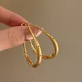 Detail view of elegant gold oval hoop earrings with black polka dot design - Matte Polka Dot Teardrop Hoop Style (61#) / Gold