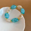 Detailansicht eines Vintage-Acryl-Armbands mit blauen und weißen ovalen Perlen - Grün