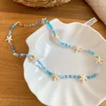 Primo piano della collana estiva con perline di stelle marine e cristalli blu su conchiglia - Collana-Blu / Blu