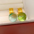 Gros plan de boucles d'oreilles boules en résine verte et menthe avec anneaux dorés en boîte - Vert Pâle