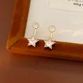 Macro view of gold-plated star and round zircon stud earrings with sparkling details - Gold