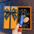 Miniature rugby ball keychain with blue strap presented in a luxury orange gift box - Rugby Ball / Orange Gift Box