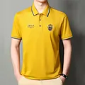 Detailansicht des gelben Herren-Poloshirts mit besticktem Wappen und gestreiftem Kragen - M / Gelb