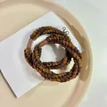Dettagliata inquadratura macro di elastici per capelli intrecciati color caffè su vassoio - Caffè Scuro