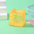 Close-up of a translucent orange glitter water cube squishy toy for stress relief - Orange Glitter Cube