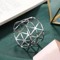 Detailed view of a silver hollow geometric metal napkin ring on green textured fabric backdrop - Geometric Triangle Hollow Style / Silver