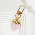Nahaufnahme eines süßen rosa Erdbeerschlüsselanhängers mit schicken goldenen Details - Vollton Rosa Erdbeere