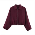 Détail d'une veste bouffante bordeaux pour femme avec une fermeture éclair argentée. - Rouge