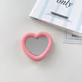 Detailed view of a stylish pink heart-shaped mirror phone grip with soft silicone finish. - Light Pink