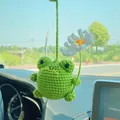 Handmade green crochet frog car mirror hanging ornament holding a small white flower - Frog And Daisy