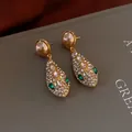 Close-up of vintage gold earrings with pearl studs and green crystal snakehead drops - Gold Blue Snake Head Drop Earrings (Silver Earring Post)