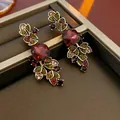 Close-up of vintage style gold-tone earrings with red and multi-colored rhinestones - Gold Red Vintage Leaf Earrings (Silver Earring Post)