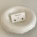 Detail view of mini green stud earrings on a white thank you card in a ceramic dish. - Grass Green