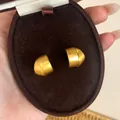 Close-up van mat geborstelde gouden oorknopjes in een bruine fluwelen sieradendoos - Goud