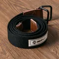 Nahaufnahme eines schwarzen Canvas-Gürtels mit Doppel-D-Ring-Schnalle und Webetikett. - Regular Fit / Schwarz