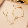 Pulsera de mano de acero inoxidable dorado con delicados dijes de flores blancas - Pulsera de Mano con Flores de Estrás (E2522) / Dorado