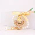 Llavero de cristal con frasco de perfume, lazo dorado y pulsera de perlas elegante - Estilo Botella Perfume Corazón / Peso 56,6 g, Longitud 11,6 * 3,9 cm / Melocotón