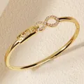Close-up detail of golden light luxury bangle with infinity symbol and LOVE engraving - Style E Gold