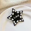 Detailansicht einer schwarzen Stern-Haarklammer mit weißem Wollrand und 'Like'-Schriftzug. - Schwarze Stern-Haarspange