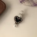 Close-up of a sweet pearl hair clip featuring a black heart with 'LOVE' engraving. - Black Heart Hair Clip