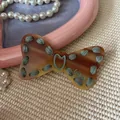 Brown tortoiseshell bow hair clip with green hand-stitched detailing and 'Like' text - Brown