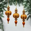 Elegant orange and gold spindle-shaped Christmas ornaments hanging on a pine branch - Matte Bronze