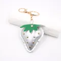 Close-up of a silver metallic leather strawberry keychain with gold studs and hardware - Punk Metal Stud Strawberry / Silver