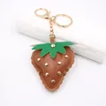 Detail view of brown leather strawberry keychain with gold studs and lobster clasp. - Punk Metal Stud Strawberry / Brown