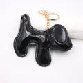 Detail view of a glossy black PU leather dog bag charm with gold-toned metal hardware - Dog Keychain / Bright Black