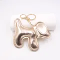 Dettaglio di un simpatico portachiavi a forma di cane con finitura in pelle PU oro rosa metallica. - Portachiavi Cane / Oro champagne