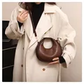 Detailed view of women's brown crescent shoulder bag with elegant crocodile pattern texture - Coffee