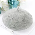 Close-up view of a minimalist grey wool beret hat placed on a white decorative book - One Size / Light Heather Grey
