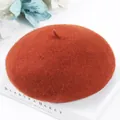 Close-up detail of a warm burnt orange wool beret with soft felt texture and classic design - One Size / Caramel color