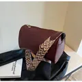 Détail d'un sac polochon bordeaux en similicuir avec une large bandoulière à motifs. - Bordeaux
