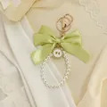 Elegant detail of a green ribbon bow keychain with pearl loop on soft fabric. - Light Green Bow (ZJ17026)