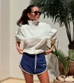 Model wearing white half-zip sweatshirt and blue athletic shorts in sunlit outdoor setting. - S / Blue