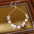 Detail showing the elegant pink pearls and cubic zirconia bow charms on the bracelet. - Pink