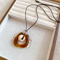 Macro view of amber resin hollow pendant with textured bead on brown cord - Spiral Texture Hollow Ring (6#) / Brown