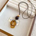 Gros plan détaillé sur des anneaux en résine ambre et perles sur cordon marron - Style Double Anneau (3#) / Marron