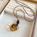 Detailed macro view of the amber translucent resin hollow pendant with a brown cord. - Irregular Hollow Ring Style (4#) / Brown