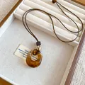Vue détaillée d'un pendentif rétro rond en résine ambrée sur un cordon en cuir brun - Anneau Creux avec Perle en Bois (5#) / Marron