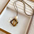 Détail rapproché d'un collier pendentif géométrique en résine dans un plateau en bois. - Style Ovale Creux (1#) / Marron