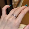 Close-up van een zilveren open ring met paars zirkoon tarwe-oor ontwerp op een vinger - Tarwe-aarlang Open Ring Stijl (K1234) / Zilver-Paarse Zirkonia