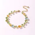 Detail view of a luxury gold bracelet featuring multi-colored teardrop and rectangular stones. - Fresh Candy Gold