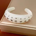 Detailweergave van melkwitte hars manchetarmband met gepolijste zilveren klinknagels - Cuff Bracelet / Broken Wit