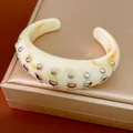Detailweergave van de hars manchetarmband met oranje marmeren textuur en studs - Cuff Bracelet / Ivoor