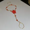 Vista detallada de una pulsera de dedo dorada con flor roja y cristales brillantes - Cadena de mano / Dorado-Rojo