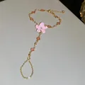 Elegante pulsera de mano dorada con una delicada flor de cerezo rosa y cristales - Cadena de mano / Oro-Rosa